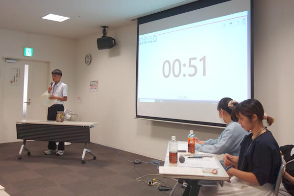 ビブリオバトル大会の司会をする長崎純心大学の学生と、大会に参加した中学生。